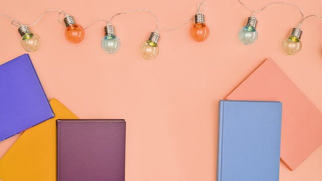 Vintage books on copy space orange background with bulb lights. Stop motion flat lay