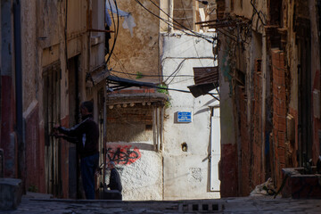 Algiers (Alger), Algeria : Street scene in the Casbah Stone stairs and ancient ottoman houses. Chiaroscuro atmosphere. Two Algerian men in the shadow.