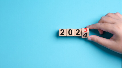 2024 Happy New Year eve wooden blocks flip change hand blue background. Countdown starting ending...