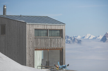 Young woma resting during weekend on a terrace of an alpine cottage above clouds.