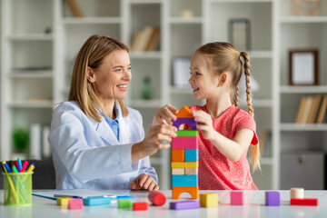 Play Therapy. Little Girl And Child Development Specialist Playing Wooden Bricks Together