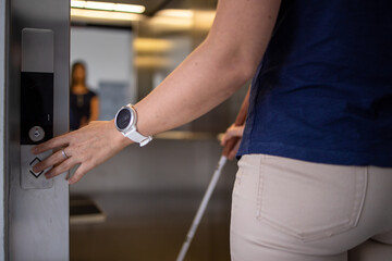 Blind woman walking on city streets, using her white cane to navigate the urban space better and to get to her destination safely