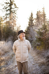 Happy senior man walking outside. Portrait of senior man in a forest on a winter day.