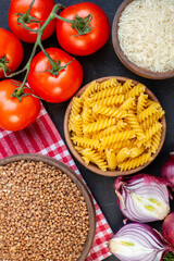 Top view of buchwheat groats on red stripped towel pastas fresh vegetables rice on black background