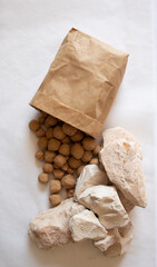 Edible caramel clay stones in brown bag with white clay stones on a white background flat lay