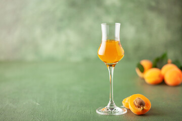 Apricot liqueur in a grappas glass and fresh apricots on the table. Copy space