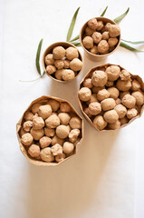 Edible caramel clay stones in brown bags with green leaves on a white background minimal flat lay