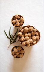Edible caramel clay stones in brown bags with green leaves on a white background minimal
