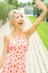 PRETTY GIRL SMILING WHILE IS TAKING A SELFIE AND CALLING BY PHONE IN THE STREET