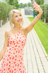 PRETTY GIRL SMILING WHILE IS TAKING A SELFIE AND CALLING BY PHONE IN THE STREET