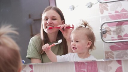 Little baby girl and mom brushing teeth in bathroom together, daily routine, dental care, hygiene