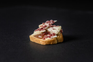 Gastronomic appetizer made cheese, jam, and bread isolated on a black background