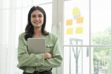 Portrait of happy young business woman holding laptop computer in office. Business people and...