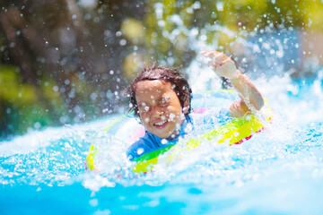 Child in swimming pool on toy ring. Kids swim.