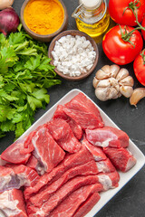 top view fresh sliced meat with seasonings greens and red tomatoes on a dark background meal dinner meat animal food butcher barbecue