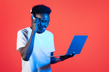 Cheerful young african man using headphones and computer