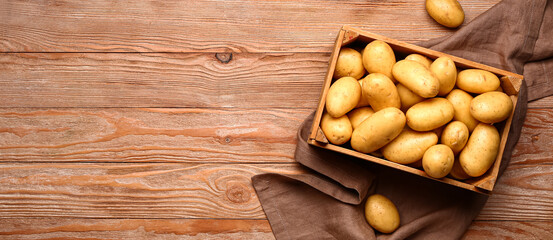 Crate with raw potatoes on wooden background with space for text - obrazy, fototapety, plakaty