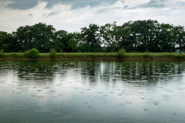 Lago com pingos de chuva sobre a água numa tarde cinzenta e nublada de primavera