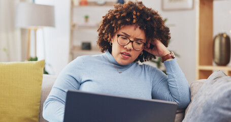 Laptop, bad news and grief with a woman on a sofa in the living room of her home feeling sad or...