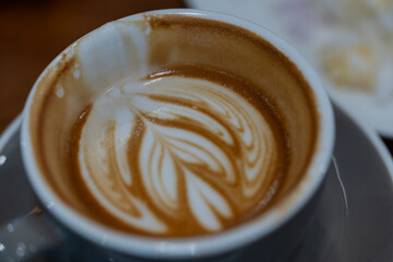 Close up a cup of hot latte art coffee on wooden table.A cappuccino is an espresso-based coffee drink with steamed milk foam.Best of menu in the coffee shop or restaurant.