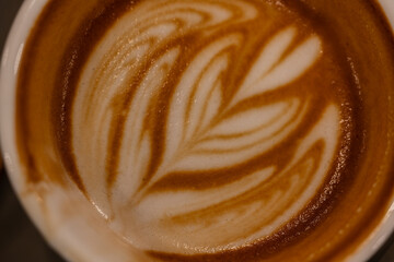 Close up a cup of hot latte art coffee on wooden table.A cappuccino is an espresso-based coffee drink with steamed milk foam.Best of menu in the coffee shop or restaurant.