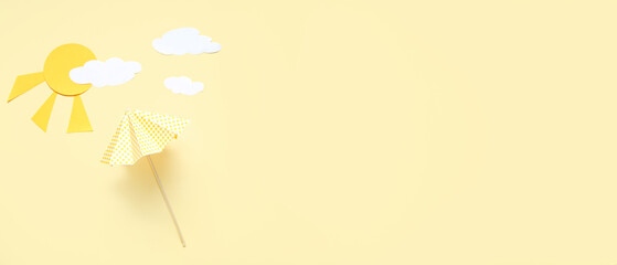 Creative composition with umbrella, paper clouds and sun on beige background with space for text