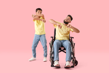 Little boy and his father in wheelchair dancing on pink background