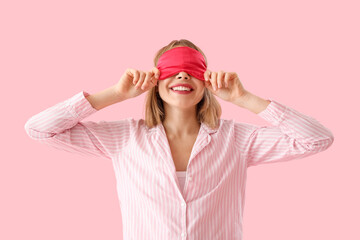 Happy young woman in pajamas on pink background