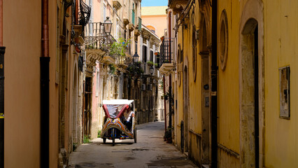 Old scooter parked in a typical Italian narrow street ,IT is an old motor bike of the city siracusa, sicily