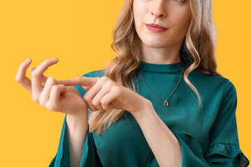 Young woman counting on yellow background, closeup