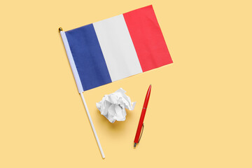 Flag of France with pen and crumpled paper on beige background