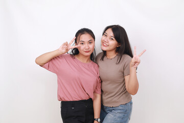 Two asian women standing while making peace hand gesture. Isolated on white background