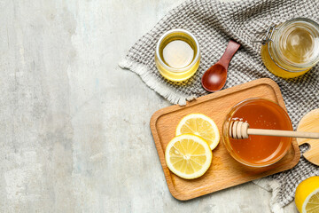 Jars of sweet honey and lemon on grey background