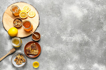 Composition with sweet honey, combs and lemon on grey background