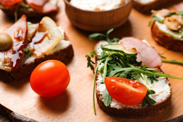 Wooden board of tasty sandwiches with cream cheese and ham, closeup