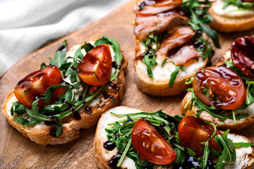 Wooden board of tasty sandwiches with cream cheese, arugula and tomatoes, closeup
