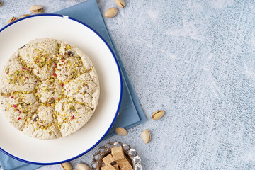 Plate of tasty Tahini halva with pistachios on light background