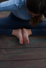 View on a girl with athletic body in blue gym suit is doing yoga exercises