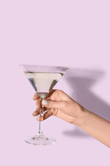 Woman with glass of martini on lilac background