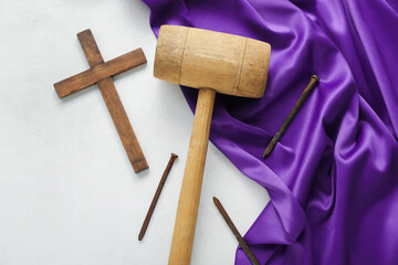 Wooden cross with mallet, nails and purple fabric on white background. Good Friday concept