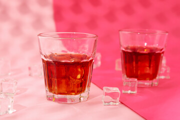 Glasses of cold rum on pink background