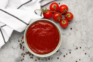 Bowl with tasty tomato paste and fresh vegetables on grunge background