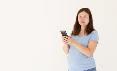 Fototapeta premium Portrait of a smiling cute pregnant woman using mobile phone isolated on a white background