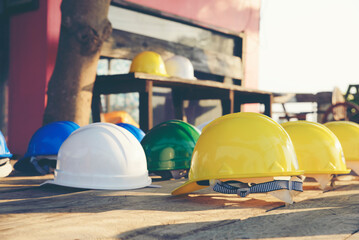 Safety helmet (hard hat) for engineer, safety officer, or architect, place on wooden floor. Yellow, White, green, blue, and orange safety hat (helmet) on construction site.