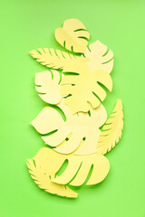 Yellow paper tropical leaves on green background