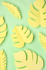 Yellow paper tropical leaves on green background
