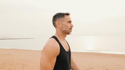 Middle-aged muscular man walks along the promenade before jogging