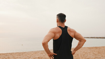 Mature man doing warm up before workout while standing on the beach, Back view