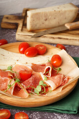 Plate with slices of tasty jamon and cheese on table