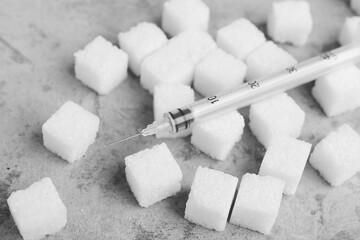 Sugar cubes with syringe for insulin injection on grunge background, closeup